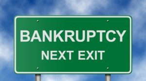 Green road sign with the words "Bankruptcy, Next Exit" in white lettering.